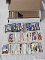 White box opened showing a large number of assorted Philadelphia Phillies baseball cards spread in front, including dozens of cards from various players and sets mostly from early 1980s.