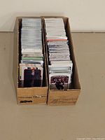 Two long cardboard boxes filled with various trading cards showing the full capacity and size of the lot.