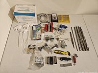 Full view of assorted tools and related items arranged on floor including drill bits, locks, testers, sprayers, cutters, respirators, grout pen, and knives.