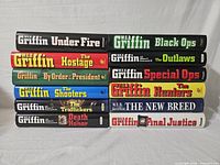 Photo of 12 W.E.B. Griffin hardcover books arranged side by side showing titles and condition.