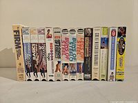 Photo showing 15 workout/exercise VHS tapes in their original cardboard sleeves, upright and aligned side-by-side, clearly displaying titles and spine artwork.
