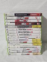 Stack of 17 Xbox 360 game cases showing titles clearly on their spines including NBA 2K series, Fight Night, NCAA Football, Madden NFL, NHL 2K, FIFA Soccer, Tiger Woods PGA Tour, and MLB 2K games.