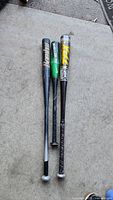 Three baseball bats laid out on the ground, showing different lengths and colors.