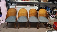 Four wooden mid-century modern style chairs with curved backs and gray upholstered seats arranged in a row.