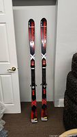 Full view of two Salomon Fire Wing Twin skis standing side by side showing overall length and top graphics.