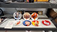 Seven Marilyn Monroe collector plates arranged on a shelf showing overall set and varied colors and poses.