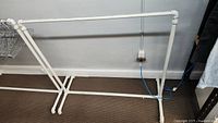 Full view of white metal clothes rack showing frame and base.