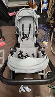 Top-down view of the double stroller showing two seats, harness straps, and canopy shades in a light grey color.