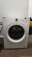 Front view of white Kenmore front-load dryer on carpeted floor