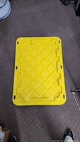Photo of yellow lid of the plastic storage tote showing grid pattern and handles.