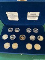 Coins arranged in blue velvet case with 14 individual coins encapsulated, depicting various Canadian 125th anniversary designs including quarters and central gold-toned coin.