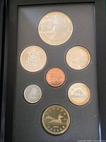 Top-down photo showing all seven coins in foam display including 50c, 25c, 10c, 5c, 1c, $1, and a silver dollar with hummingbird