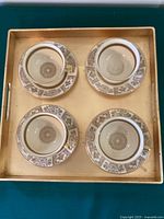 Overhead view of four teacups and saucers arranged on rectangular gold tray