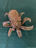 Front view of the green beaded octopus wire sculpture showing detailed beadwork and shape.