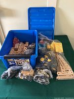 Blue bin filled with assorted Brio wooden building pieces and separate bags of bolts, wheels, and connectors displayed around it