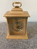 Front view of gold-tone Bulova carriage clock showing ornate dial with Roman numerals and Tempus Fugit inscription.