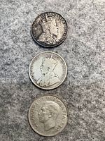 Obverse sides of three Canadian half dollar coins from 1904, 1929, and 1949 showing portraits of monarchs.