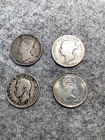 Top and reverse sides of four Canadian quarters arranged in two rows on a gray felt surface.