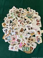 Top view of a large pile of Canadian stamps affixed to torn pieces of paper showing a wide variety of designs and sizes.