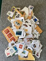 Photo showing diverse Canadian stamps, including wildlife and symbol-themed stamps on small torn paper pieces and some envelope parts arranged on a gray surface.