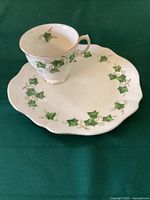 Top view of the Colclough teacup placed on the sandwich plate showing the ivy leaf pattern and gold trim on both items.