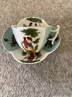 Top angled view of the demitasse cup with lovers scene and quatrefoil edges on saucer