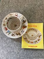 Full view of teacup, saucer, and guide book showing cover