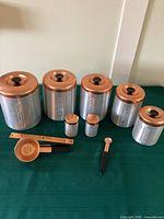Full set showing five canisters, salt and pepper shakers, measuring cups, and grease canister with strainer