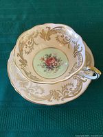 Top view of teacup inside saucer showing gold filigree and peach cabbage rose