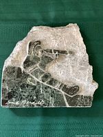 Full view of the verdi green marble sculpture carved with a figure of a polar bear hunter holding a rifle, signed by David Bernett.