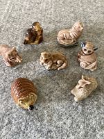 Top-down image showing all seven ceramic animal figurines arranged on grey background, various browns and natural glazings visible.