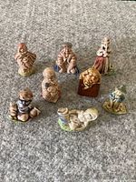 Front view of 8 hand-painted ceramic Red Rose Tea nursery rhyme figurines arranged on carpet.
