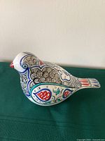 Side view of the hand painted ceramic bird showing colorful intricate traditional Turkish designs on the body and tail with a red beak.