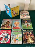 Eight vintage children's books arranged on a green surface, titles visible and illustrating a children's classic book collection.