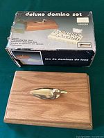 Photo of original product box with image and features printed, showing the oak chest with brass duck and deluxe domino set with brass swivels.