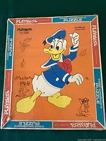Front view of the unopened Playskool Donald Duck wood puzzle box showing Donald Duck on an orange background with illustrations of leaves and animals