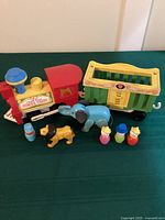 Full set of the vintage Fisher Price Little People Circus Train parts, including engine, cage car, elephant, lion, and three small people figures.