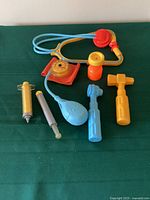 Complete view of all Fisher-Price 1980s medical kit toys on green surface.
