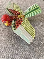Top-down angle showing the colorful lithographic details of the tin bird with wings spread.