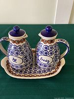 Full set showing oil and vinegar cruets on matching tray with hand painted blue and brown decoration