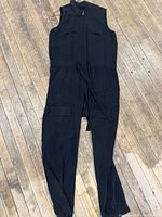 Full view of black sleeveless jumpsuit laid flat showing length and design
