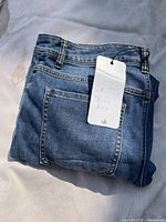 Folded blue denim jeans with rear pocket visible
