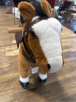 Front view of plush ride-on horse showing head, handles and hoof wheels