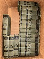 Box containing sixteen green cloth Mark Twain volumes showing spines and volume numbers