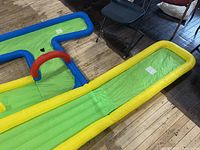 Inflatable course section with green putting lane edged yellow, blue side rail and red arch