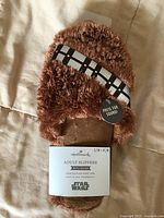 Front view of packaged Chewbacca slippers showing bandolier strap, sound button tag, size S/M