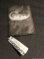 Front of Tyvek passport cover showing Batman logo and attached Dynomighty tag