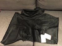Full view of black alpaca scarf laid out on couch, tags visible