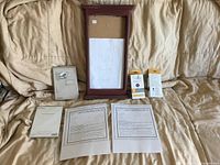 All lot contents laid out: framed signboard, two invitation packs, two UV detector dot packs, printed gift certificate pages