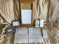 All items arranged: voucher, invitations, UV detector dots, wooden signboard